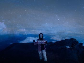 Full length of man sitting on rock at night