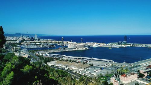 High angle view of city by sea against clear blue sky