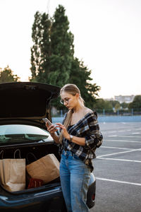 Shopping, sale, happy young stylish blonde woman with shopping bags opening car after shopping. girl 