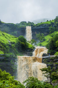 Scenic view of waterfall against sky