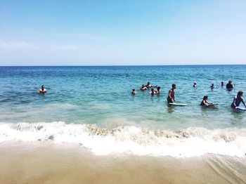 People enjoying at beach against clear sky