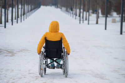 Rear view of woman on wheelchair at park during winter