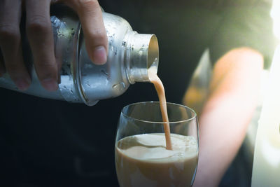 Close-up of hand pouring drink in glass