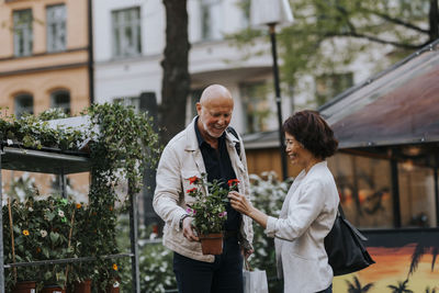 Smiling male and female senior friends buying plant from nursery