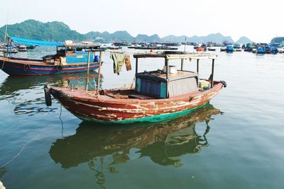 Fishing boats moored on sea against sky