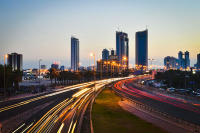 Light trails on road in city against sky