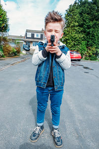 Portrait of man photographing with umbrella standing on road