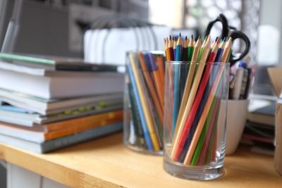 Close-up of colored pencils in glass on table