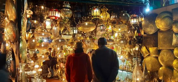 Rear view of people at illuminated market stall