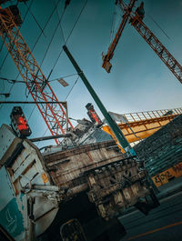 Low angle view of crane at construction site against sky