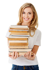 Smiling young woman holding books against white background