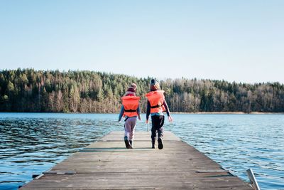 Rear view of people walking on lake against sky