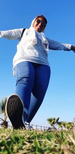 Low angle view of woman standing on field against clear sky