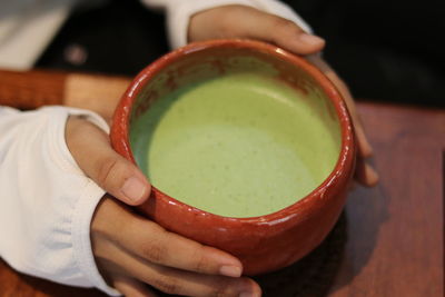 Close-up of hand holding bowl of table