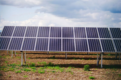 Low angle view of solar panels on field against sky
