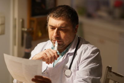 Thoughtful mature doctor reading paper in hospital