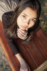 Portrait of young woman sitting on wood