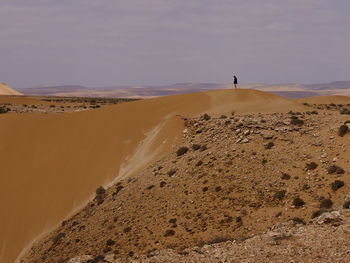 Remote woman on sand dune in the desert