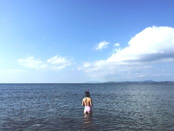 Rear view of man standing in sea against sky