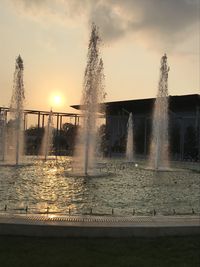 Water splashing fountain against sky during sunset