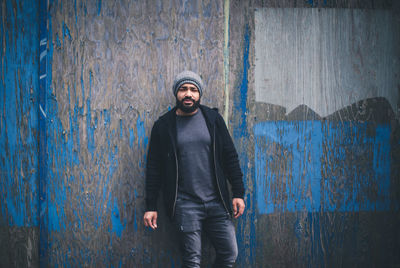 Portrait of young man standing against wall