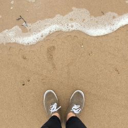 Low section of man standing on sand