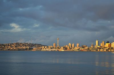 Sea by cityscape against sky