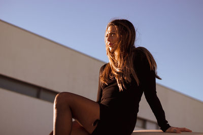 Midsection of woman sitting against clear sky