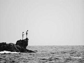 Man standing with daughter by sea on rock