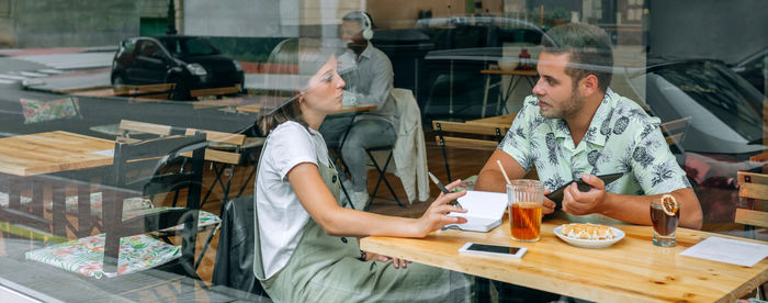 Young woman using mobile phone while sitting on table
