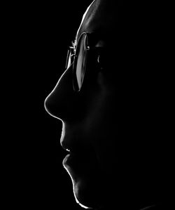 Close-up of young woman against black background