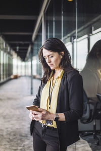 Female entrepreneur using smart phone while standing at workplace