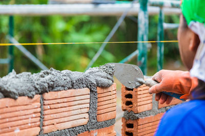 Construction worker putting cement mortar on top of stacked terra cotta bricks