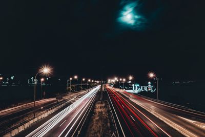 Light trails on road against sky at night