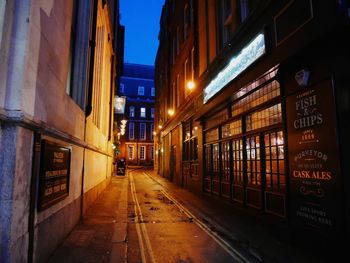 Illuminated alley amidst buildings in city at night