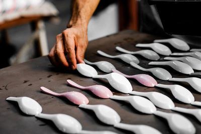 Cropped hand of man setting spoons on wooden table