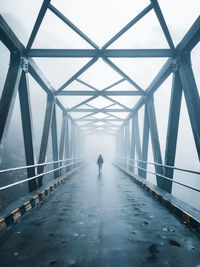 Rear view of man walking on bridge