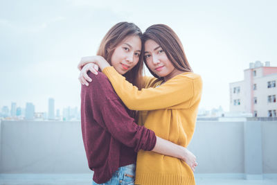 Close-up portrait of friends embracing while standing outdoors