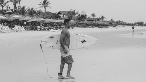 Rear view of man with surfboard on beach