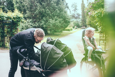 Father peeking in baby carriage on footpath during sunny day