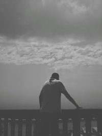 Rear view of man looking at sea against sky