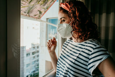 Close-up of woman standing by window at home