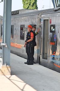 Full length of men standing on railroad station platform by train in city