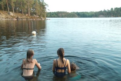 Rear view of two women swimming in lake