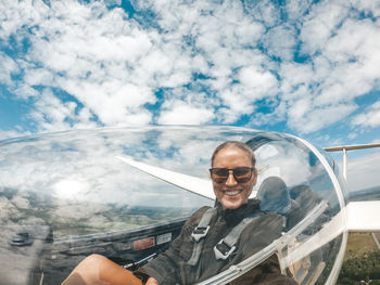 Portrait of woman flying airplane against cloudy sky