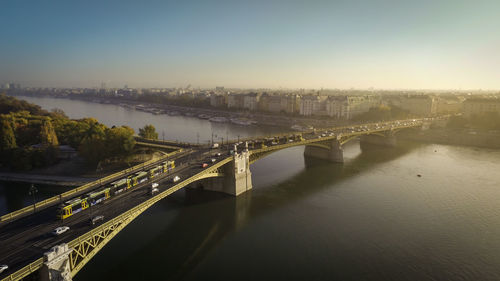 Bridge over river in city against clear sky