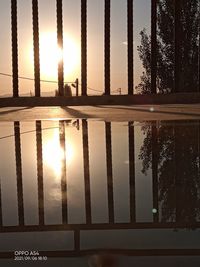 Silhouette plants by swimming pool against sky during sunset