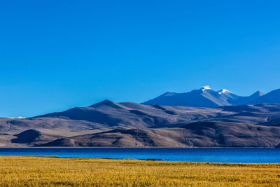 Scenic view of lake and mountains against clear blue sky