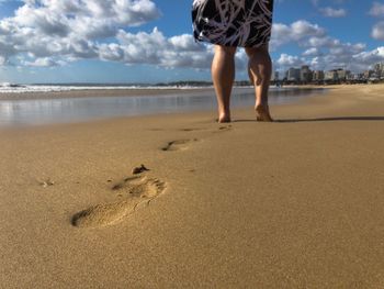 Low section of man walking on beach