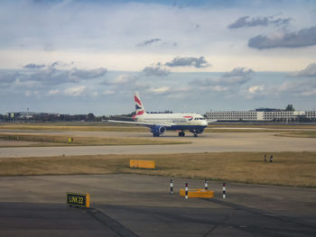 Airplane on airport runway against sky